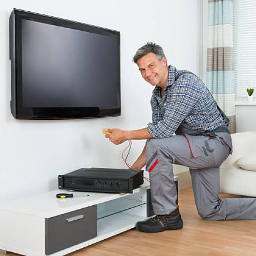 Full length of male technician installing TV set top box at home
