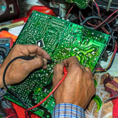 Repairing and checking of old TV motherboard with multimeter at home on the table.Close up view.